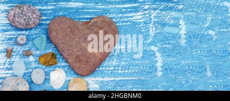 Sea pebbles and seashells on the table. A pyramid of sea stones on a blue background. Stock Photo