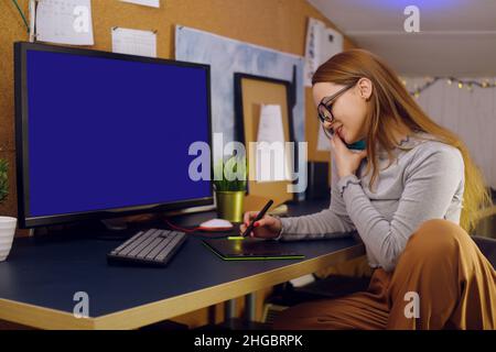 Girl works at home, graphic tablet, girl looks at a computer, green screen. Stay at home. Talking on the phone Stock Photo