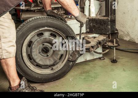 Mechanic repairing a wheel using tools in a garage Stock Photo