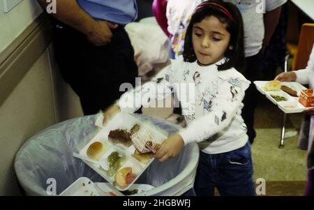 Austin, Texas  USA  1990:  Hispanic kindergarten student throwing away food after lunch.  No release.   XX Stock Photo