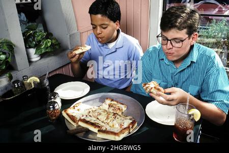 Austin, Texas USA 1990: Hispanic and Anglo boys, 15, eating pizza at a local restaurant in Austin after school treat.  MR Stock Photo