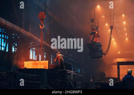 Metallurgy plant interior. Foundry worker on big mold for iron cast. Heavy industry. Steel factory. Stock Photo