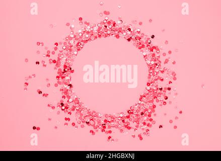 Sequins multicolored confetti lined in round frame pink background. Abstract festive composition place for text Stock Photo