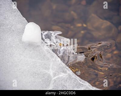 Close-up of ice on a cold winters morning starting to form on the surface of the water in a creek with air bubbles frozen in the ice. Stock Photo