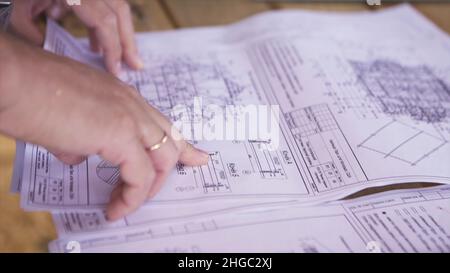 Close up view on hands pointing at technical drawings lying on the table. Man hands indicating some details in papers, constructors at work Stock Photo