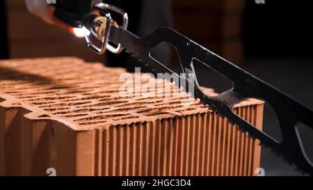 Close up of electric cutting machine for small ceramic blocks turning on before cutting. Worker uses automatic saw to cut ceramic blocks. Stock Photo