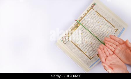 Hands Making Dua In Front of an Open Holy Quran Stock Photo