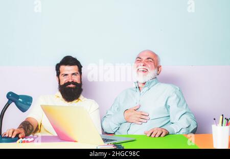 Couple of two young office workers laugh looking at laptop screen. Happy diverse colleagues laugh watching funny content on computer. Stock Photo