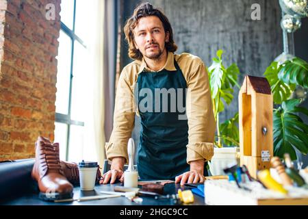 handsome tanner master tailor in a work apron workking in own studio Stock Photo