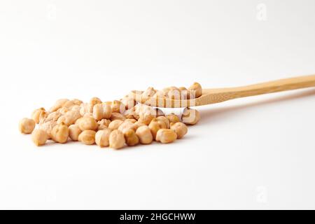 A pile of chickpeas on a wooden spoon and scattered on the white surface Stock Photo