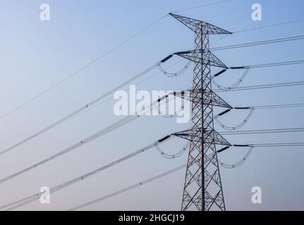 High voltage power transmission pole under the blue sky in the morning Stock Photo