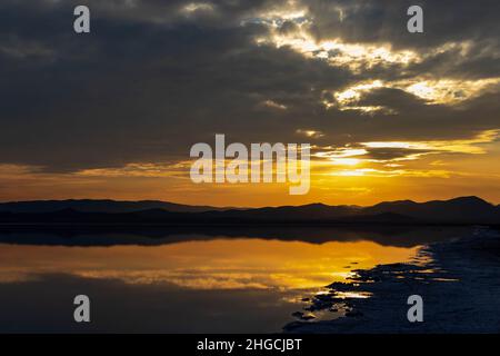 The sun shines from behind the clouds over the lake Stock Photo