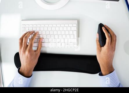 African American Man With Wrist Pain Using Ergonomic Vertical Mouse Stock Photo