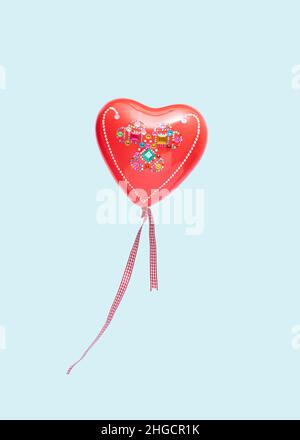 Decorated red heart shaped balloon with ribbons isolated on a blue background. Valentine day concept. Rectangle with copy space. Stock Photo