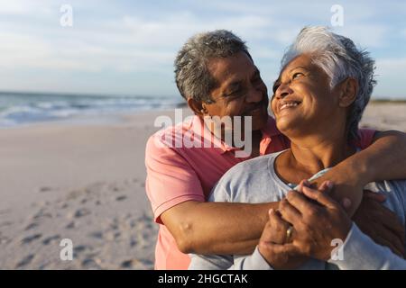 Happy senior biracial couple looking at each other while embracing during sunset Stock Photo