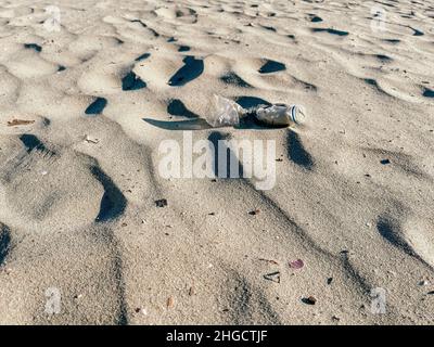 Used plastic bottle in the sand on the seashore.  Stock Photo