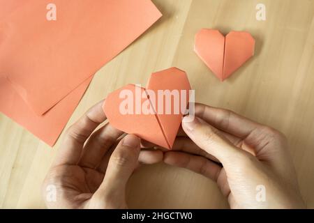 Folding Origami heart from pink paper Stock Photo