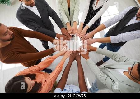 Diverse employees join hands engaged in teambuilding Stock Photo
