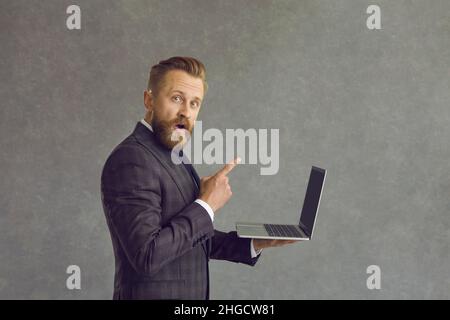 Young caucasian businessman feeling joyful and surprised holding laptop Stock Photo