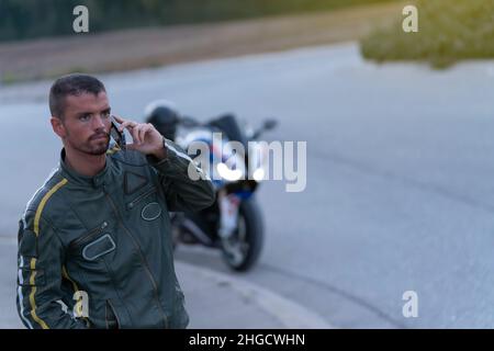 Young man with motorcycle breakdown on the road talking on the phone Stock Photo