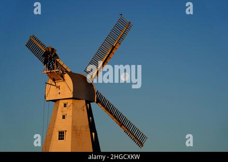 Willesborough Windmill, a white smock mill built in 1869 is bathed in the morning sunshine as the moon sets behind in Ashford, Kent. Picture date: Thursday January 20, 2022. Stock Photo