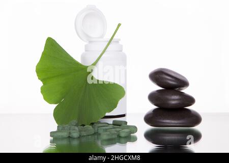 Ginkgo Biloba pill extract and fresh green leaves of Ginkgo Biloba with open container are best suited for older adult alternative medicine ads. MOCKU Stock Photo