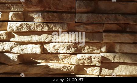 Sunny background of brown masonry decorative stone for the fireplace. Stock Photo