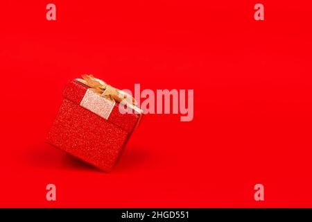 Gift box with golden bow. Red background. Stock Photo