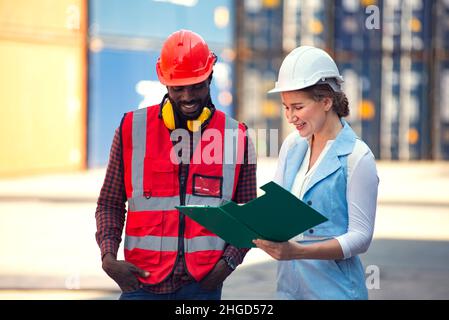 Businesswoman and engineer talking and checking loading Containers box from Cargo freight ship for import export. shipping in docks. Stock Photo
