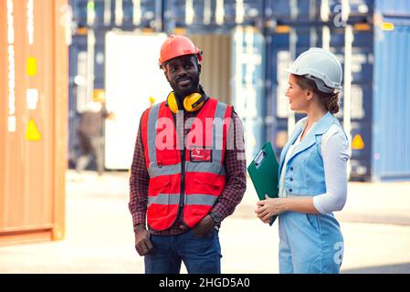 Businesswoman and engineer talking and checking loading Containers box from Cargo freight ship for import export. shipping in docks. Stock Photo