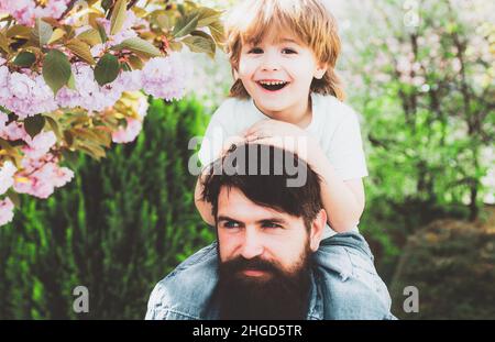 Two generations ages: father and son piggyback ride together. Happy father and son. Happy childhood concept. Stock Photo