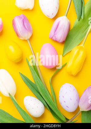 Easter greeting card. Multicolored easter eggs and tulips on yellow background. Easter concept Stock Photo