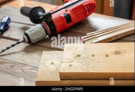 Drilling wood. Electric drill tool and planks on carpenter work bench table closeup view Construction industry, Stock Photo