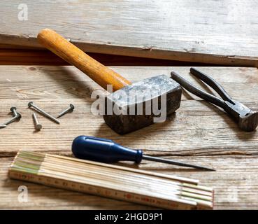 Vintage tools old used, hammer, plincers, measure and nail on wood. Carpenter work bench table, closeup view, joinery workshop Stock Photo