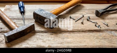 Hand tools old used, hammer, sledgehammer plincers and nail on wood, carpenter work bench table, closeup view Stock Photo