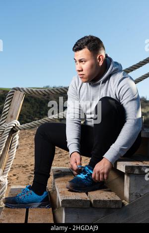 Focused latin man tying sportshoes before training. Stock Photo