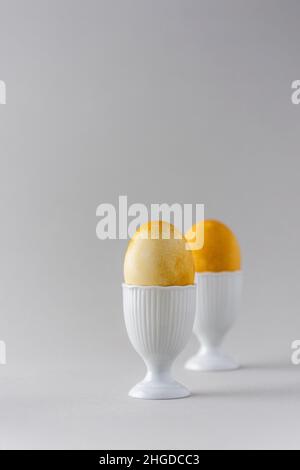 Easter painted yellow eggs in white special forms for eggs on gray background, Easter concept Stock Photo