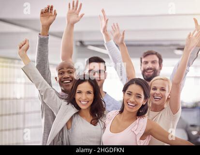 Meet the dream team. Cropped portrait of an enthusiastic business team standing with their arms raised. Stock Photo
