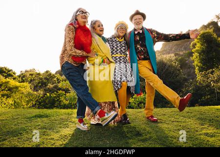 Carefree senior citizens having fun while standing together in a park. Group of cheerful senior friends wearing colourful casual clothing. Happy elder Stock Photo