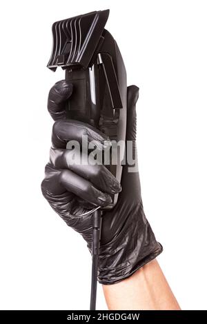 Hairdressers hand in black rubber glove holds hair clipper. Isolated on white background, close up Stock Photo