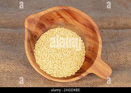 Dry organic millet in a wooden bowl on a burlap. Stock Photo