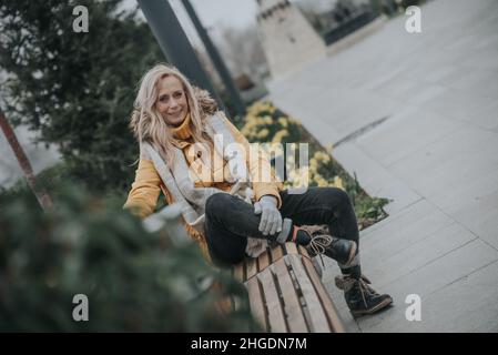 Aged pretty woman sitting on a park bench Stock Photo