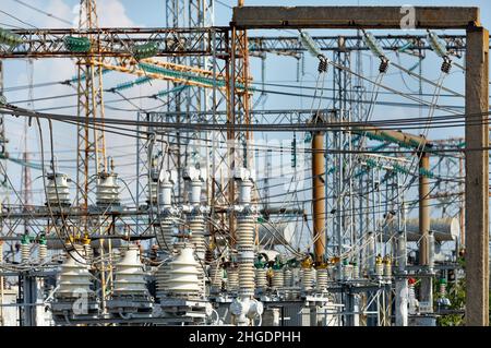 A web of electrical wires and high-voltage dielectric insulators on the metal masts of a substation on a light day. Stock Photo