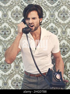 Get it done, NOW. A handsome man in retro 70s clothing shouting at someone on the phone. Stock Photo