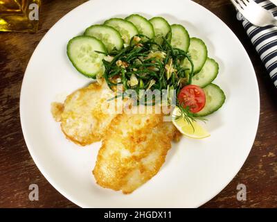 Low Carb Pan Fried Fish Fillets coated in Egg with Cucumber and Sea Weed Salad Stock Photo