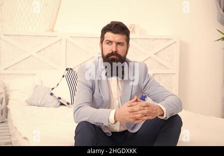 On wedding anniversary. Bearded man in wedding style sit on bed. Hipster wait in wedding suite. Formalwear and party wear. Fashion and style. Wedding Stock Photo