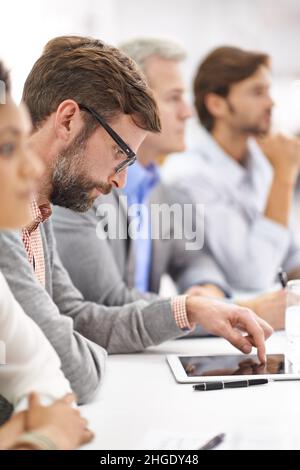 Other things on his mind. Shot of a group of dedicated business professionals sitting in a row. Stock Photo