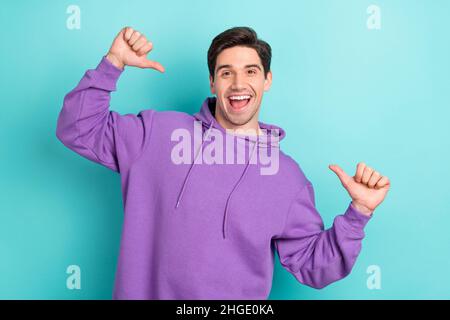 Photo of impressed funny young guy dressed violet sweatshirt pointing fingers himself isolated turquoise color background Stock Photo
