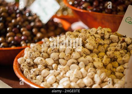 Bowls of marinated garlic cloves and olives on sale at a French market Stock Photo