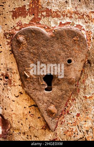 Antique heart shaped metal key hole on an old  red painted rustic door Stock Photo